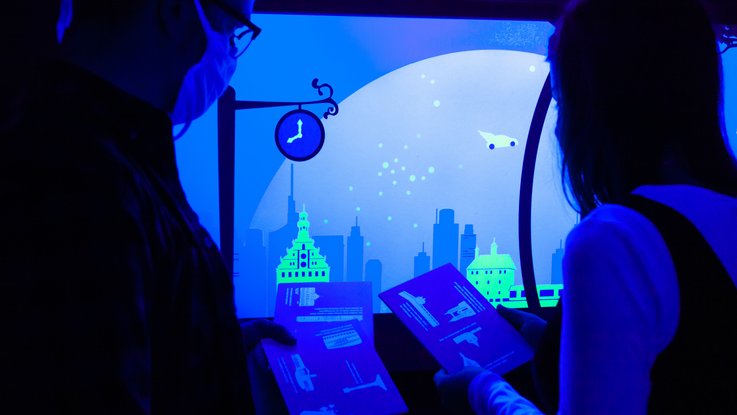 VISUELL Szenografie: Escape-Ausstellung: Durch den Einsatz von Schwarzlicht können zwei Besucher Details auf einer blauen Wand erkennen