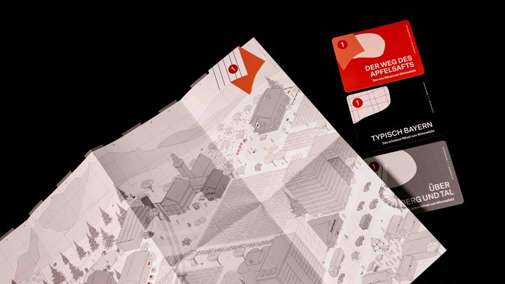 VISUELL Szenografie: Pädagogische Lernkiste: Wimmelbild mit drei verschiedenen Rätselkarten in rot, grau und schwarz Aufschrift: Lernkiste, Ernährung in Zeiten des Klimawandels