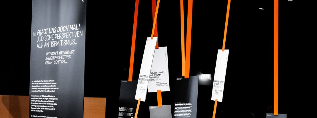 VISUELL Szenografie: Sonderausstellung: Intervention „Anti Anti 2.0“ VISUELL Szenografie: Sonderausstellung: Anti Anti 2.0: Mehrere Interventionselemente mit schwarzen Tafeln und weißen Texten; Bänder erzeugen eine räumliche Struktur und lenken die Wahrnehmung neu.