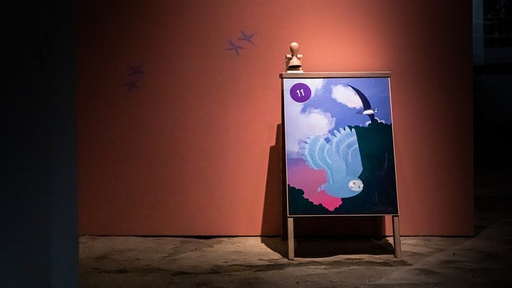 VISUELL Szenografie: Ausstellung „Spurensuche“: Stempelstation der Eule, mit Leitsystem, bestehend aus Eulen-Fußabdrücken, an der Wand