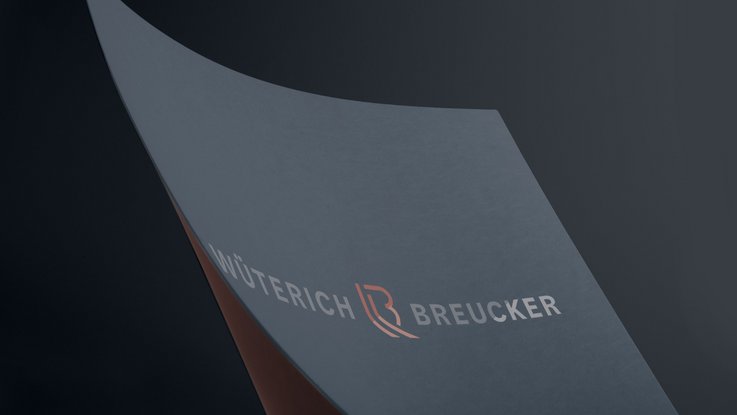 VISUELL Kommunikationsdesign: Corporate Design für Wüterich Breucker Rechtsanwälte VISUELL Kommunikationsdesign: Corporate Design: Nahaufnahme der mit Heißprägefolie veredelten Wort-Bild-Marke auf dunkelblauem Papier