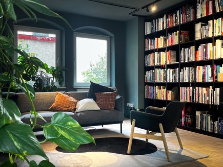 VISUELL Historie: 2023: Die VISUELL Bibliothek mit schwarzem Regal und grauem Sofa